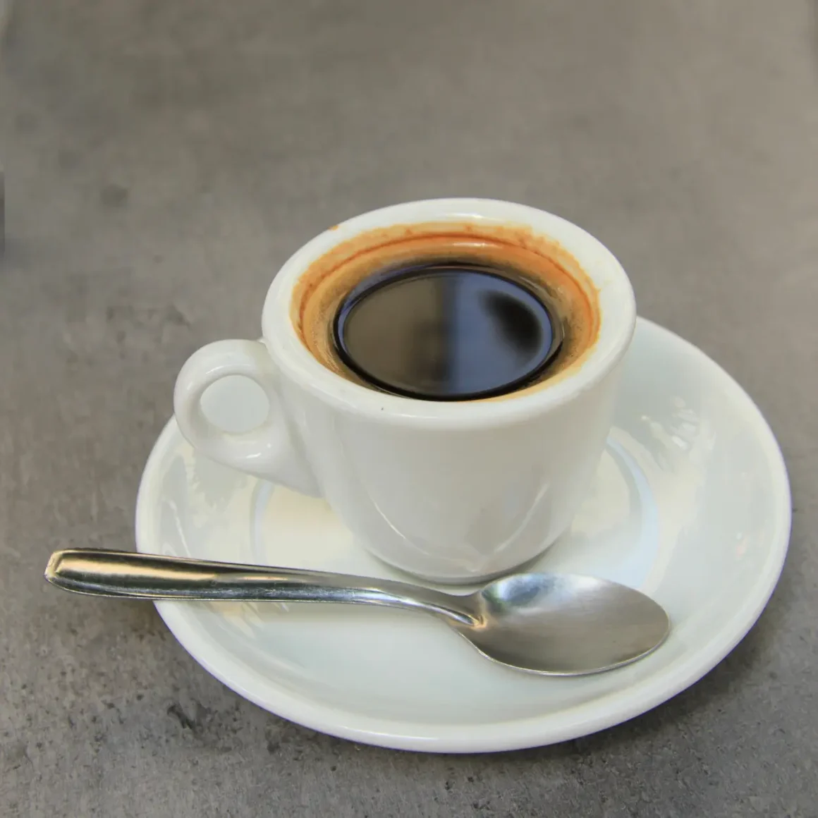 a cup of dead shot of espresso with a spoon on a saucer