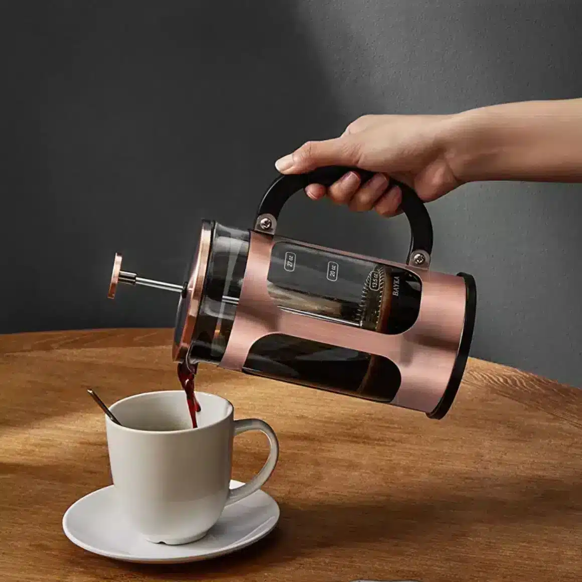 a hand pouring a coffee into a cup