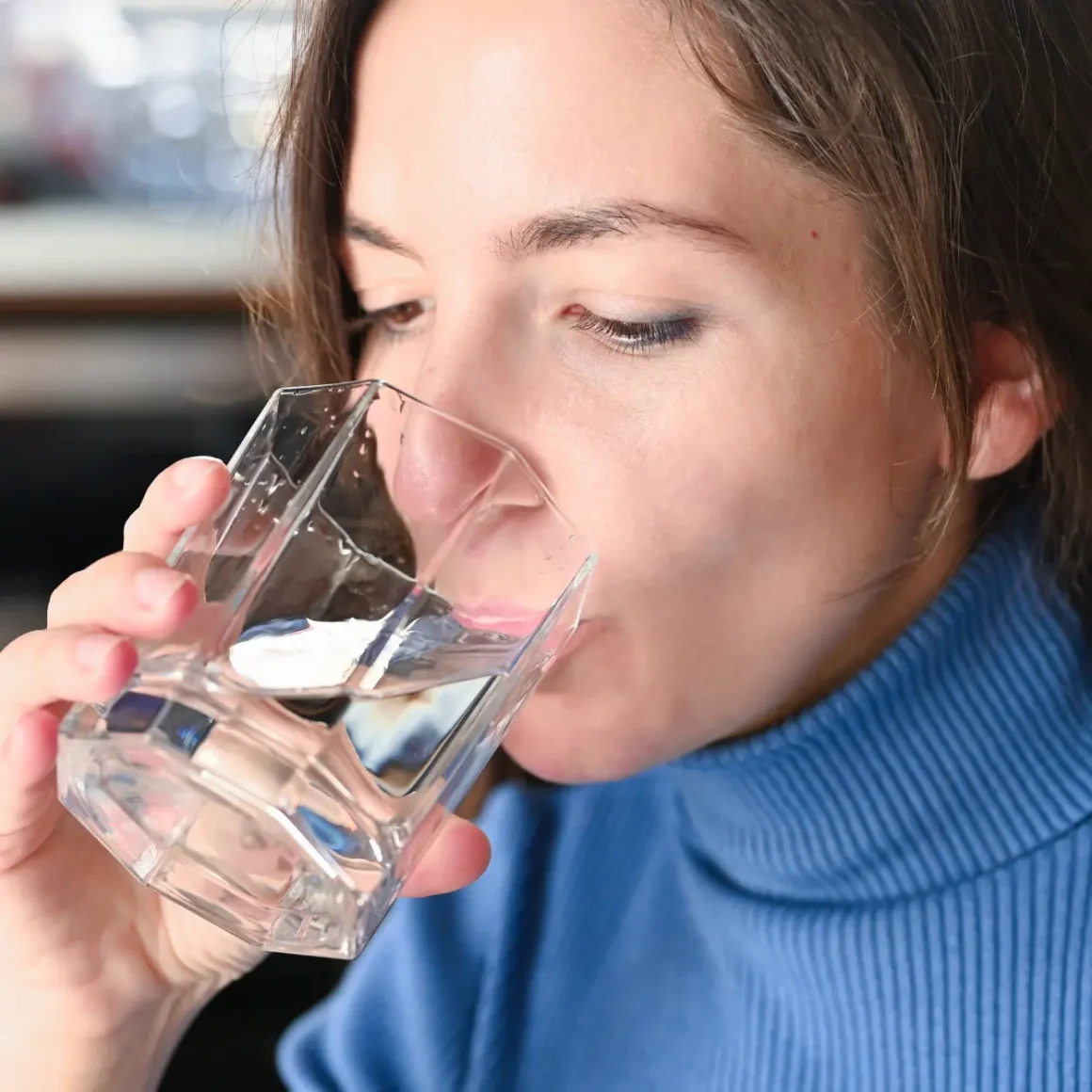 a woman drinking water from a glass for cooling her burnt tongue
