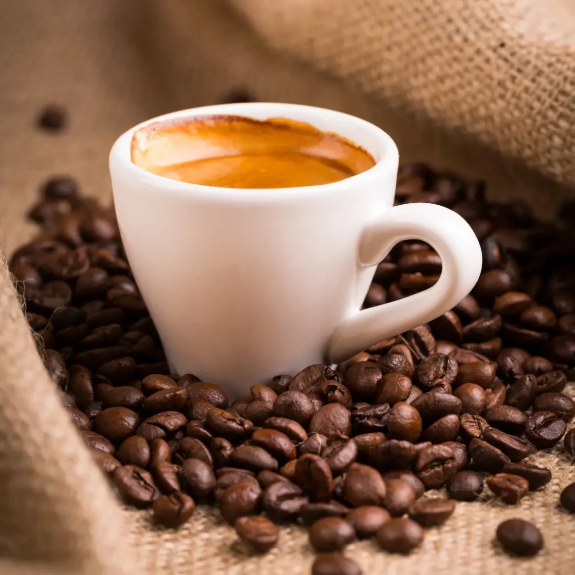 a cup of regular espresso in a pile of coffee beans