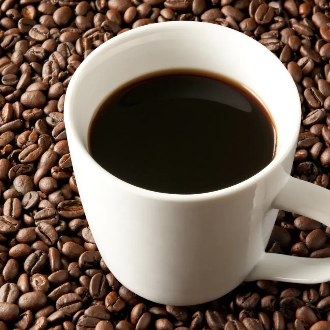 a cup of coffee on roasted coffee beans