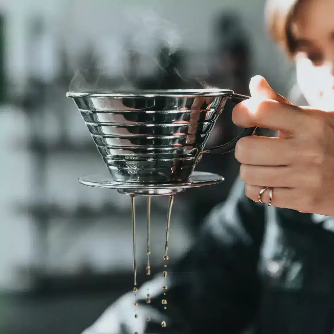 a person holding a metal funnel of kalita wave pour-over coffee maker