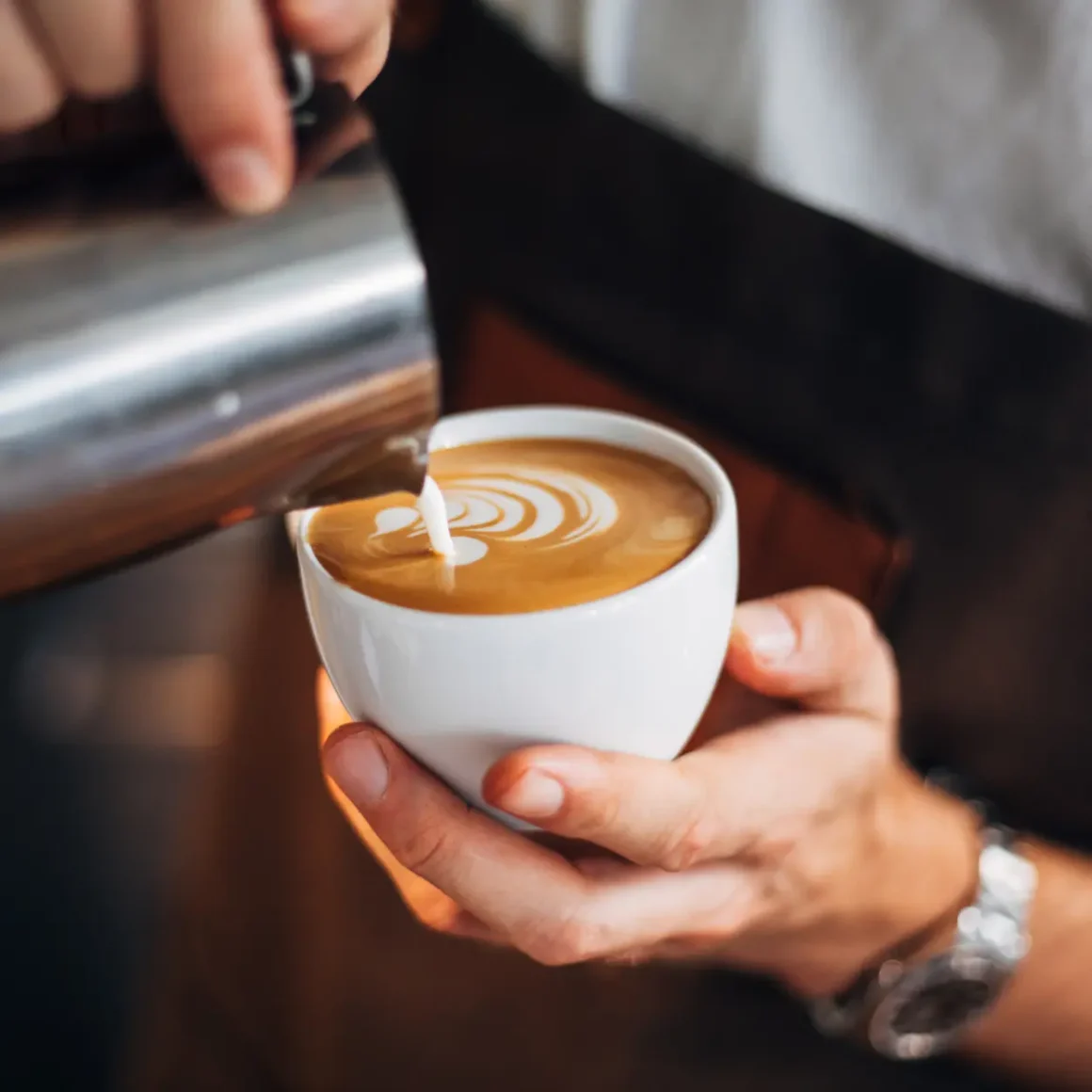 barista making a latte art into a cup