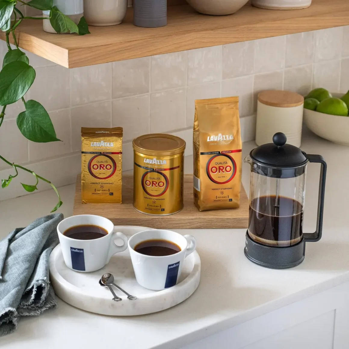 a coffee maker and cups of lavazza qualita oro coffee on a counter