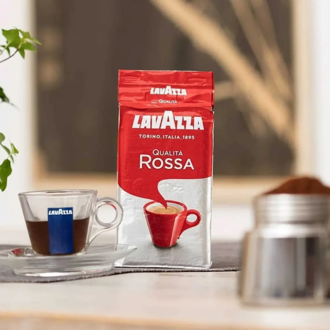 a bag of qualita rossa lavazza coffee next to a cup of coffee