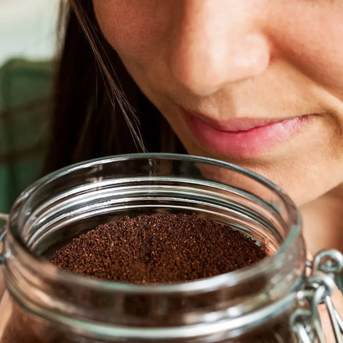 a person smelling a jar of coffee