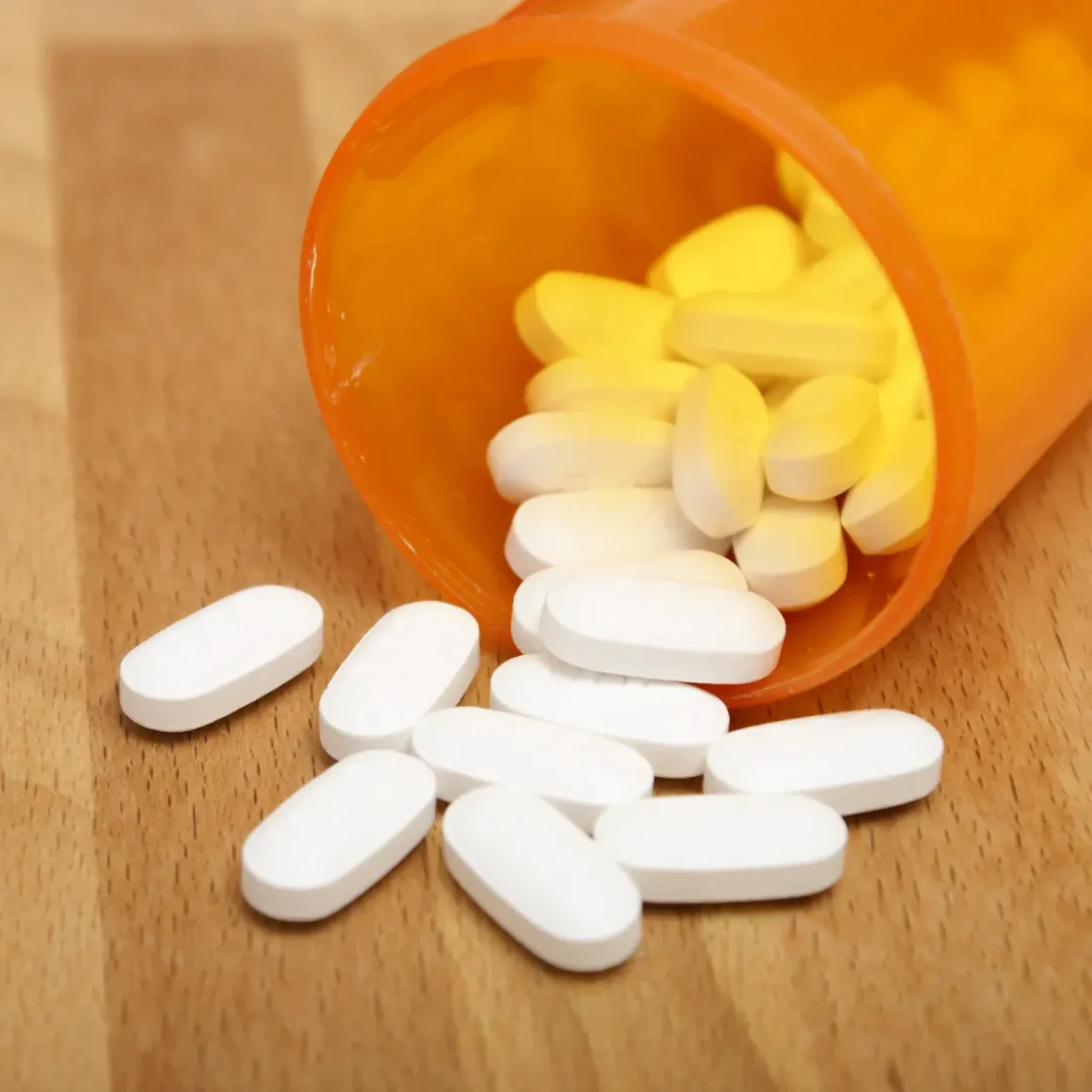 a white pills spilling out of a pill bottle