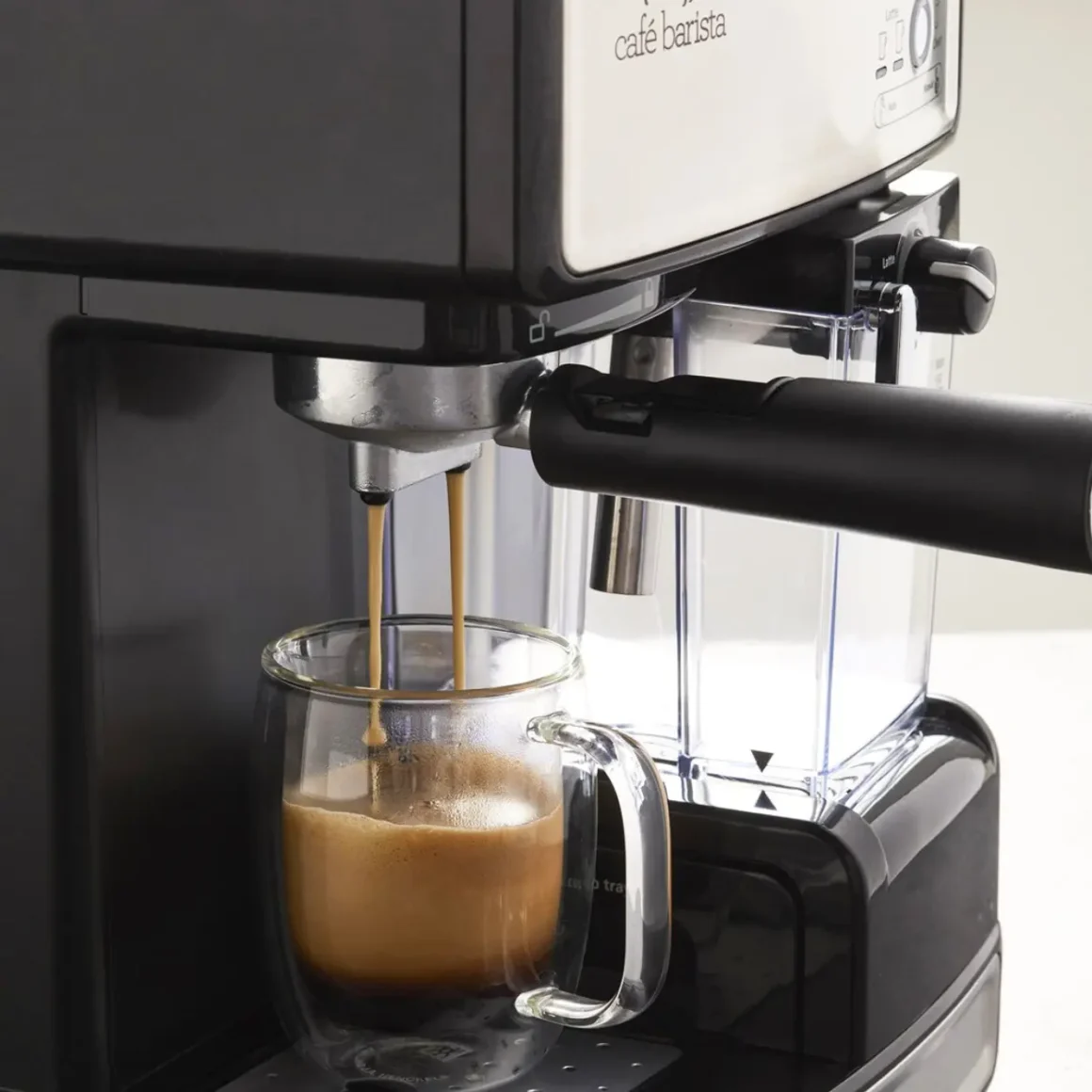 an espresso machine pouring coffee into a glass cup