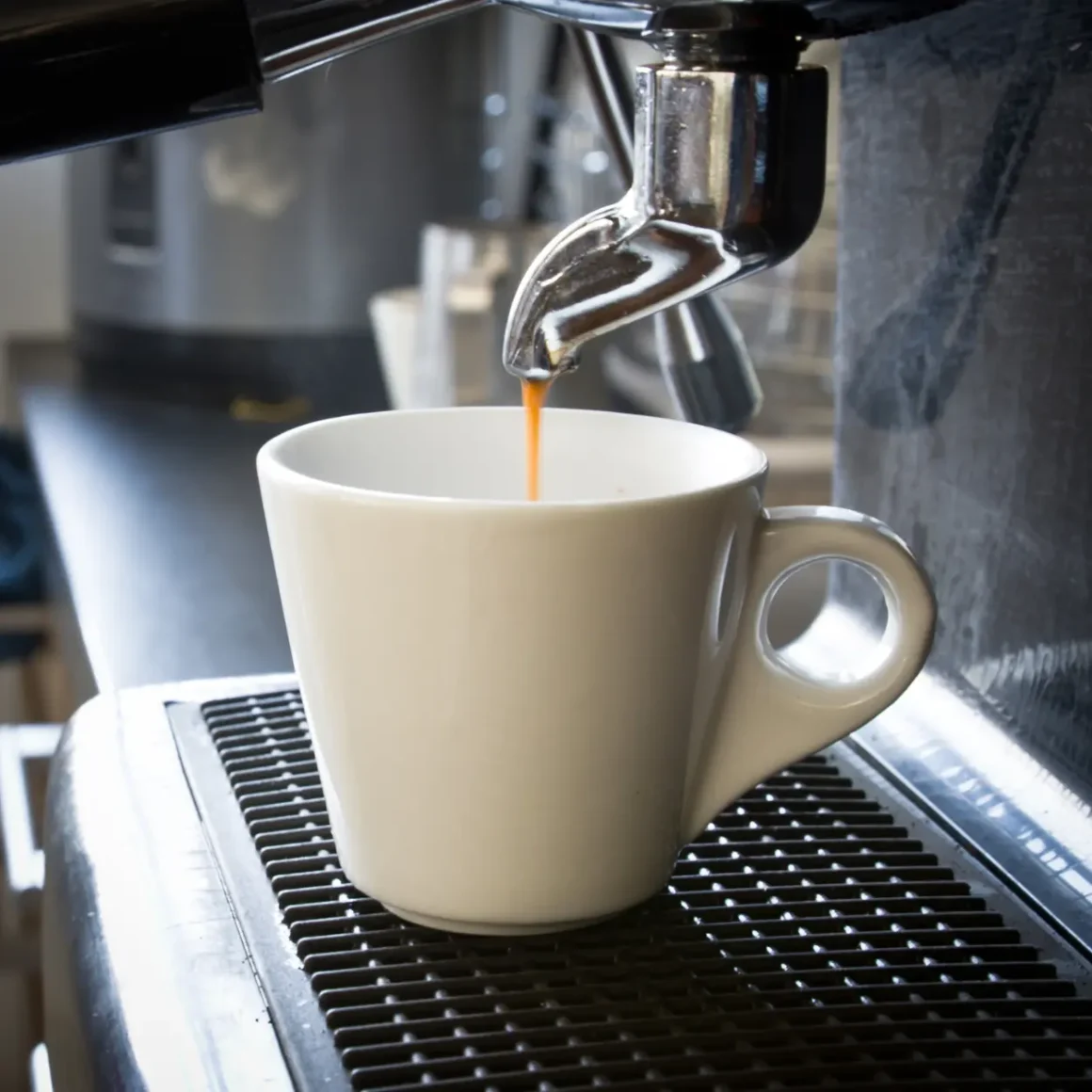 an espresso machine pouring blonde espresso in a white cup