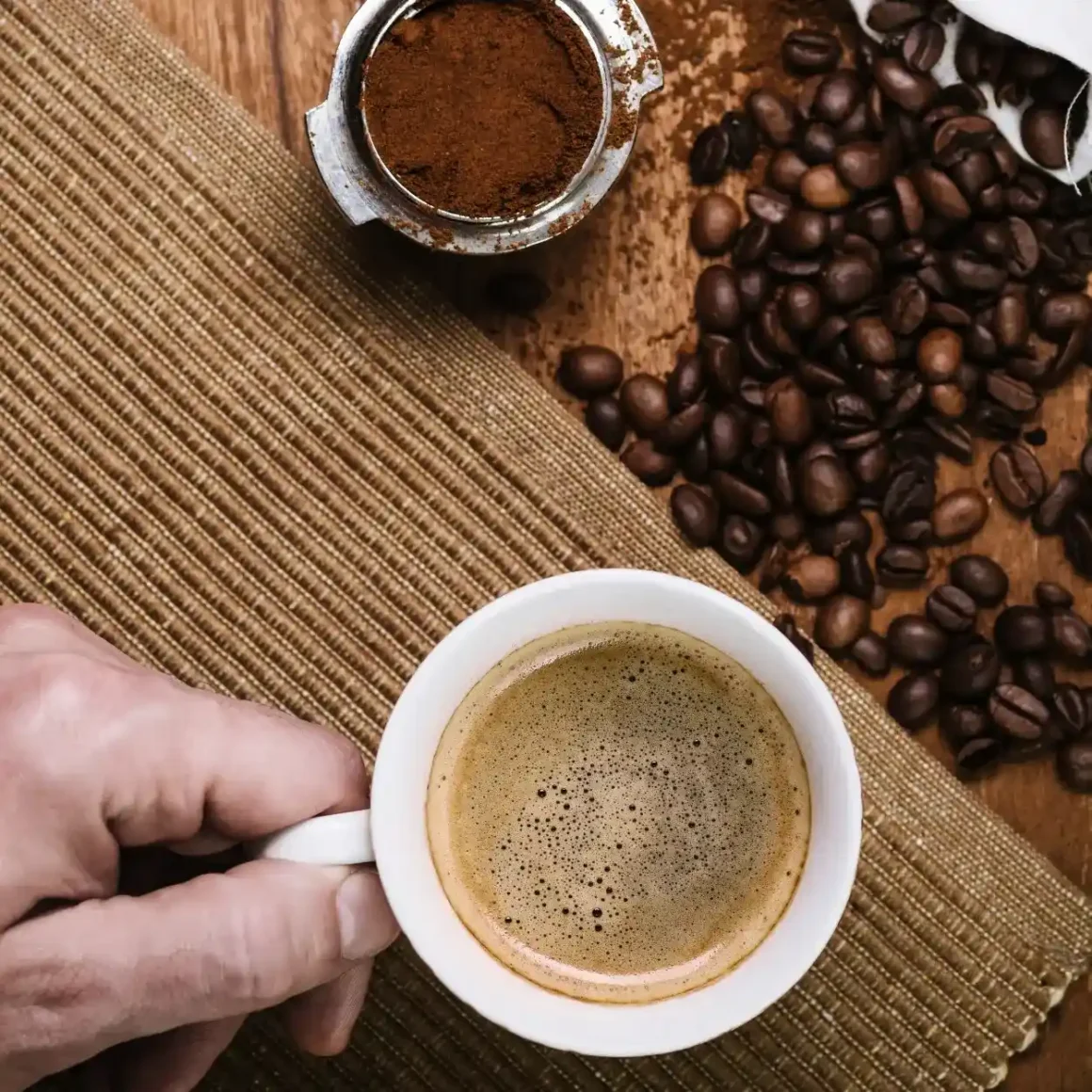 a hand holding a cup of espresso coffee