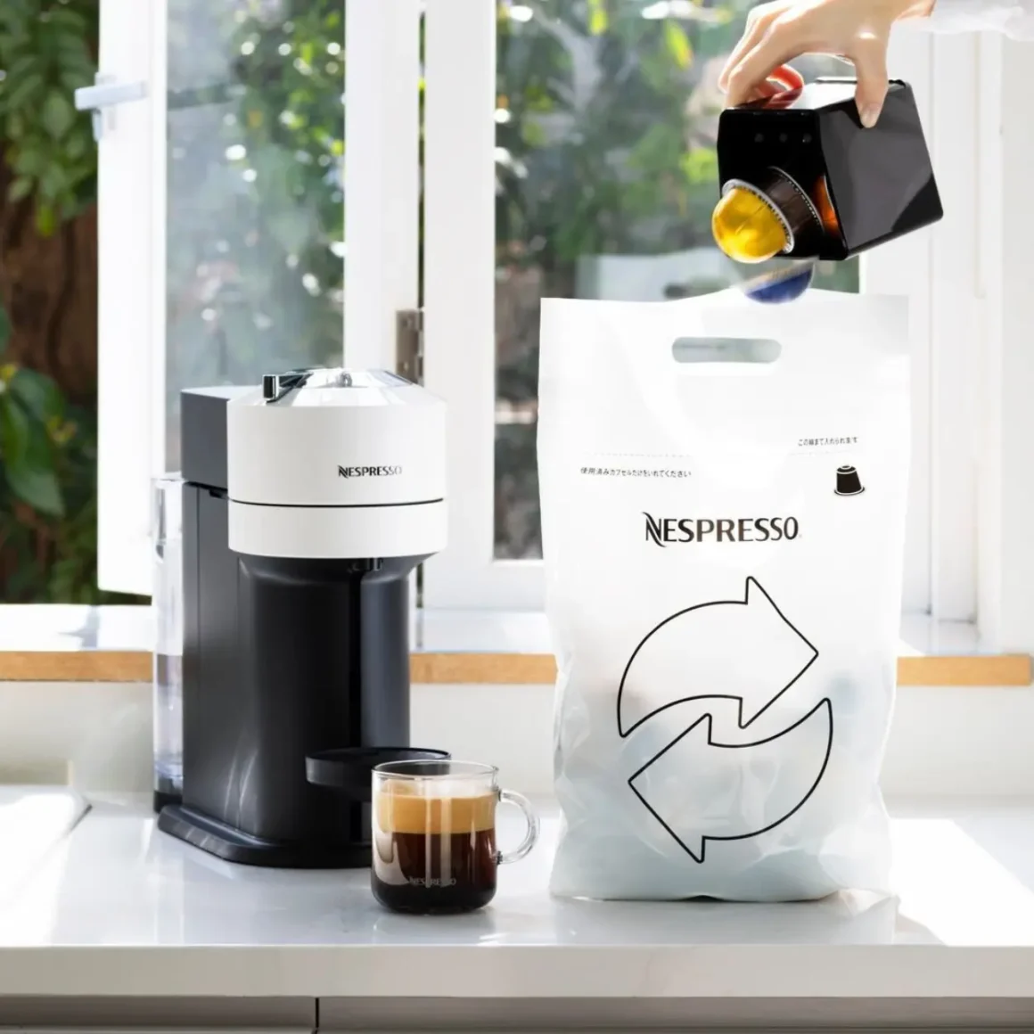 a nespresso vertuo next coffee machine with a cup of coffee and a bag