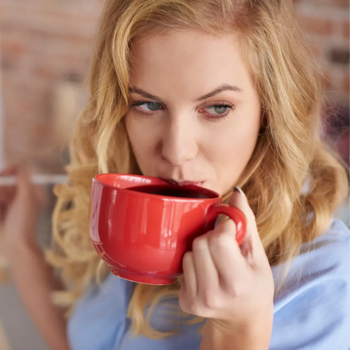 a woman drinking from a red mug
