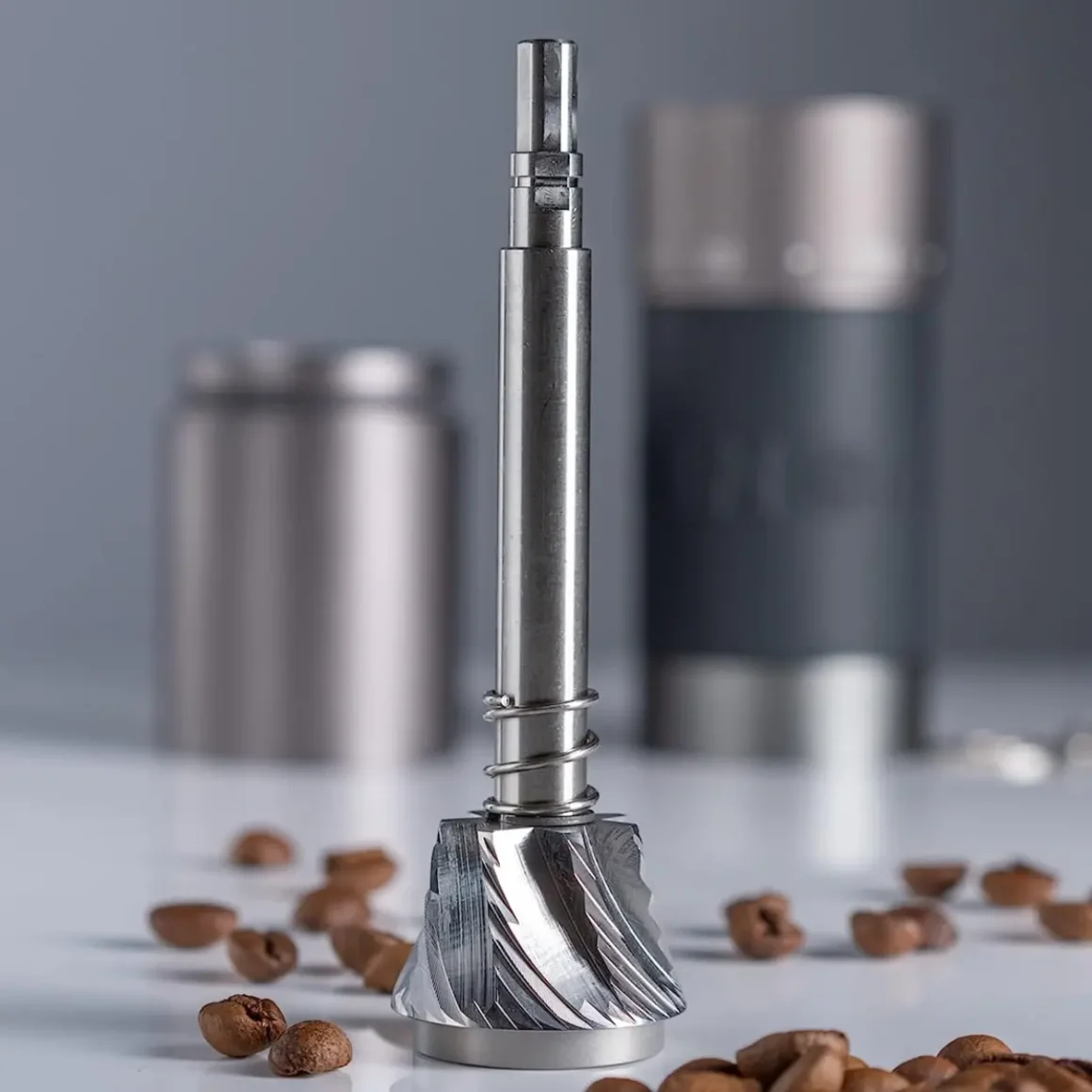 a coffee grinder part and coffee beans on a counter
