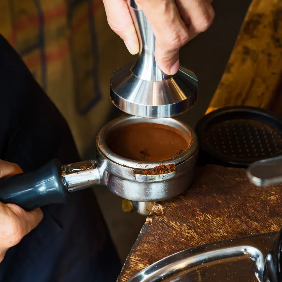 barista holding a portafilter filled with ground coffee