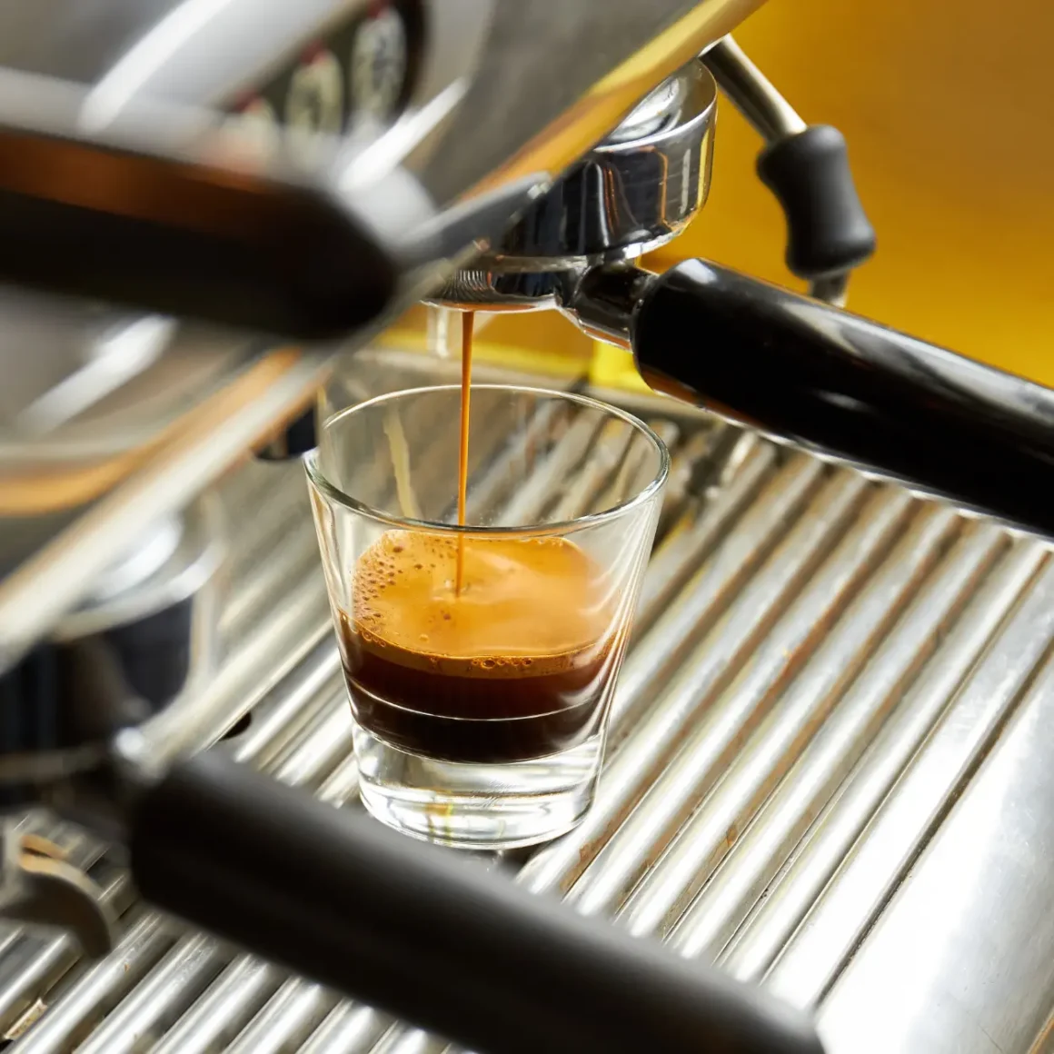 an espresso machine pouring espresso in a shot glass