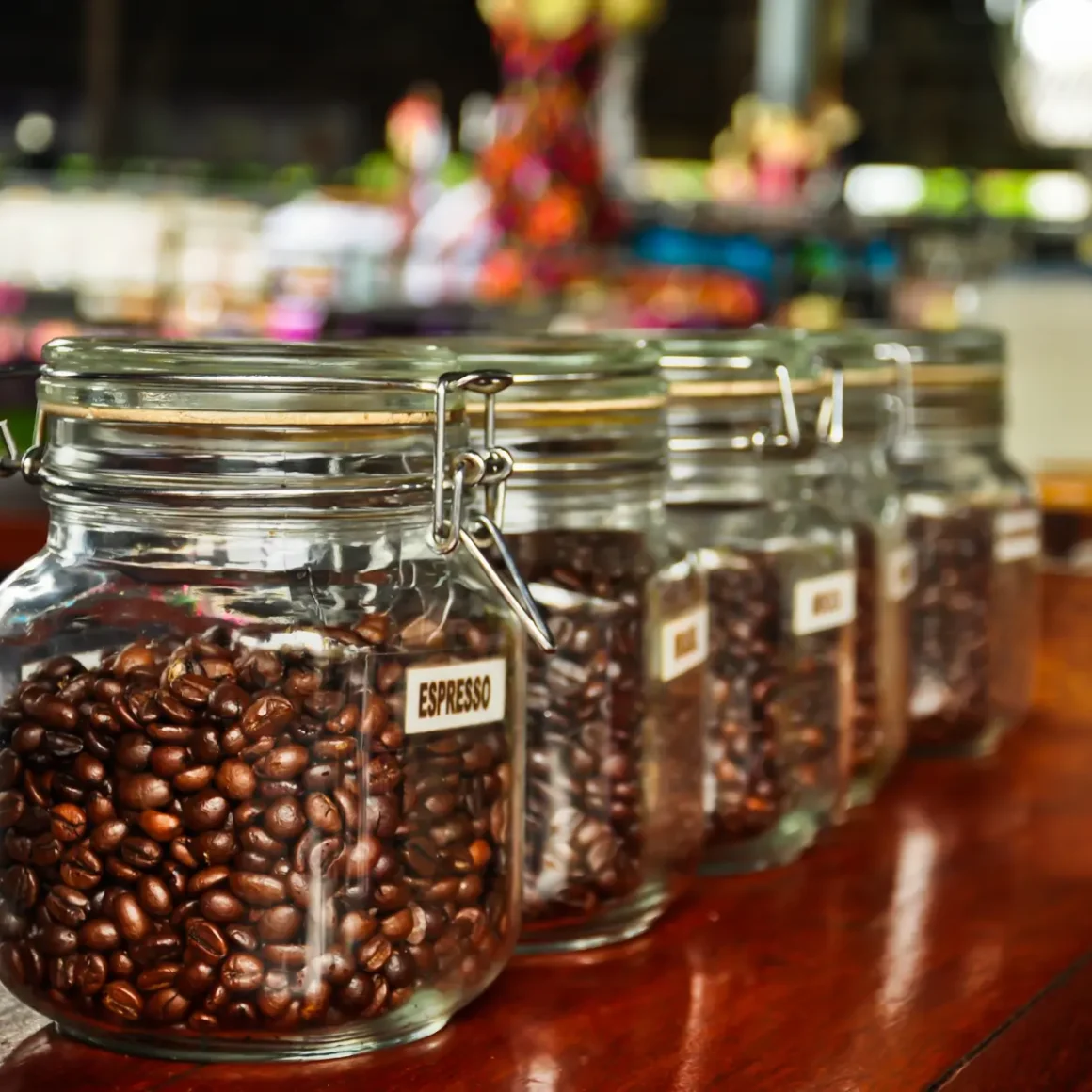 a row of glass jars filled with roasted coffee beans