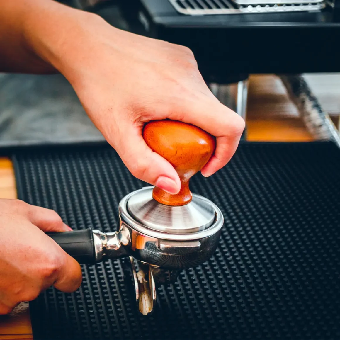 barista using a tamer to press coffee filled in a portafilter