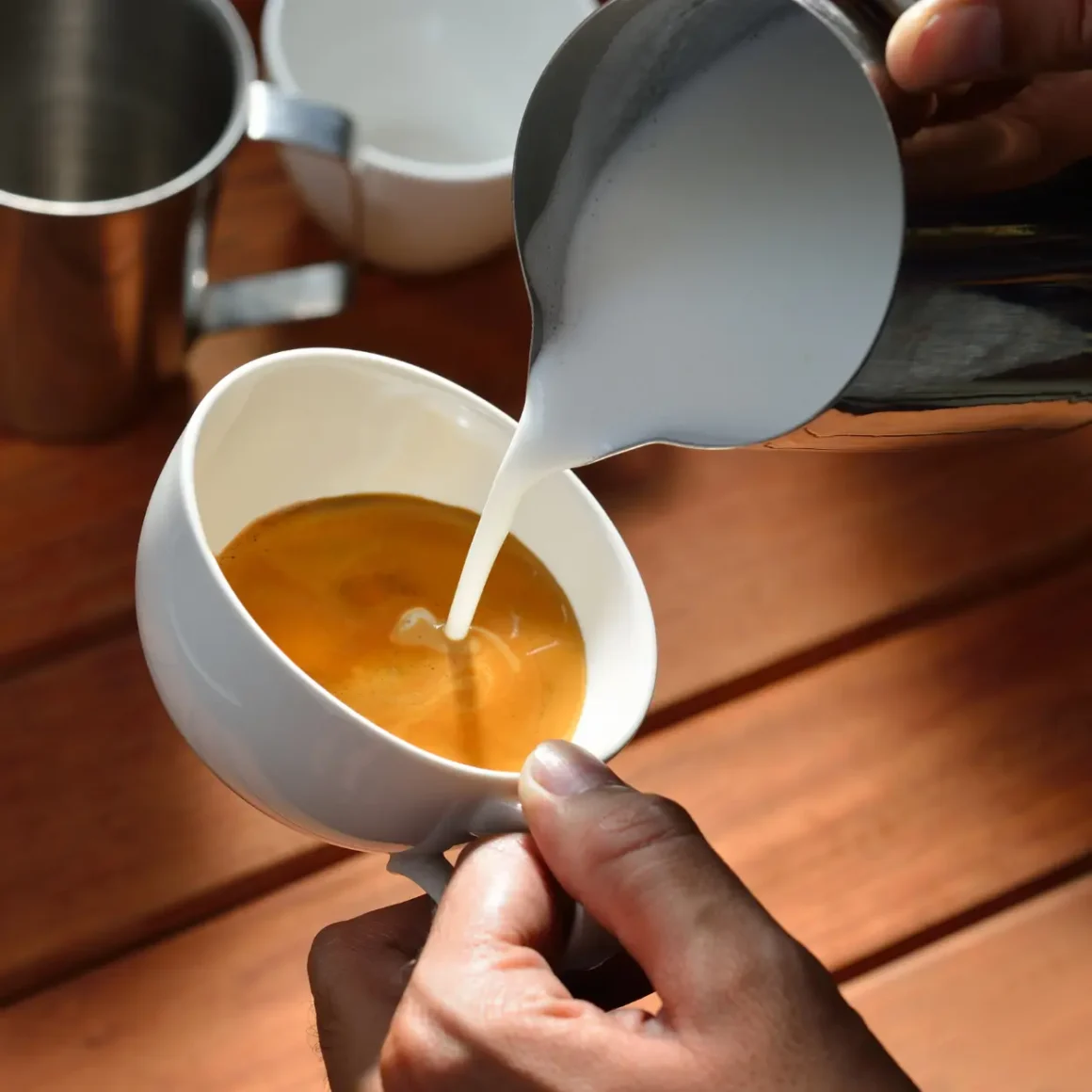 barista pouring milk into a cup of coffee