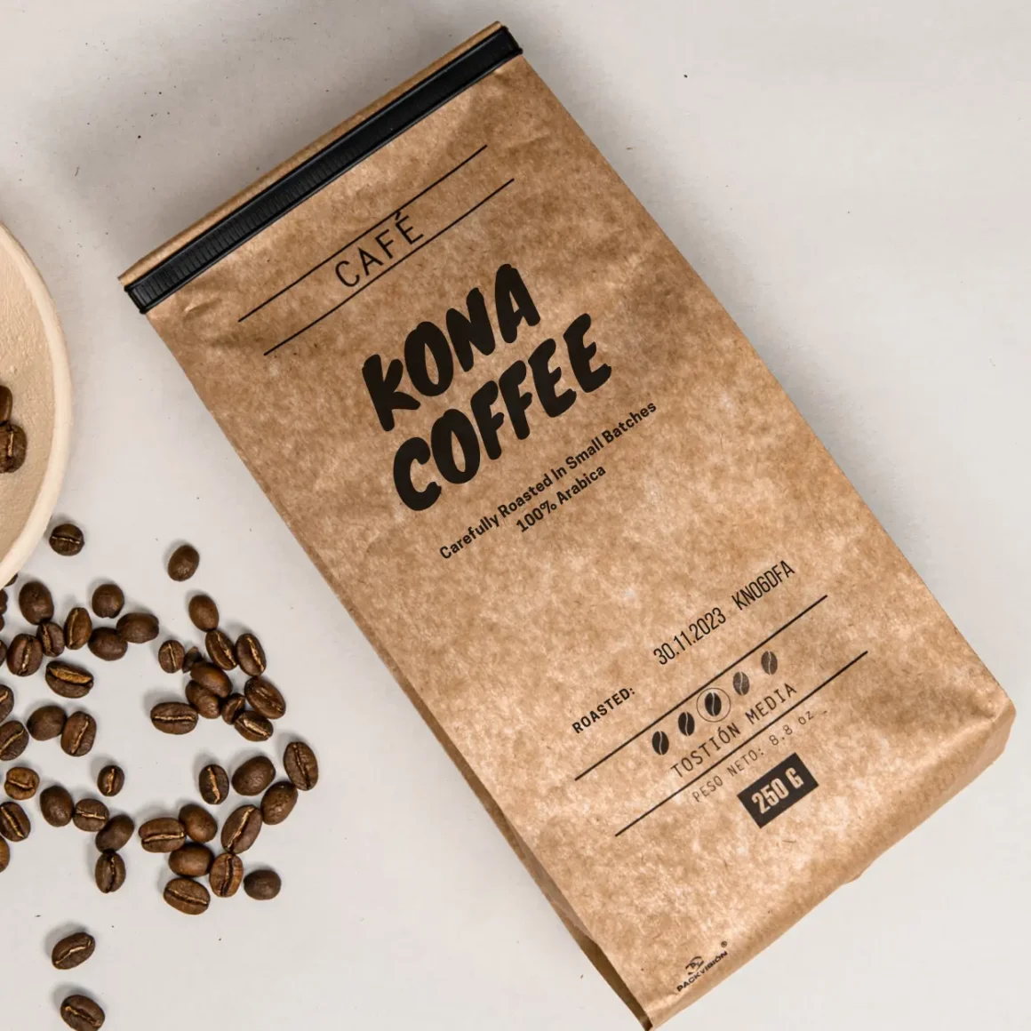 a bag of roasted kona coffee next to a bowl of coffee beans