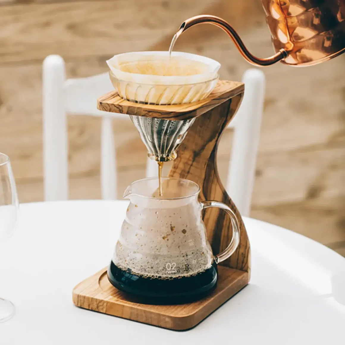 barista pouring water into pour-over coffee wooden stand