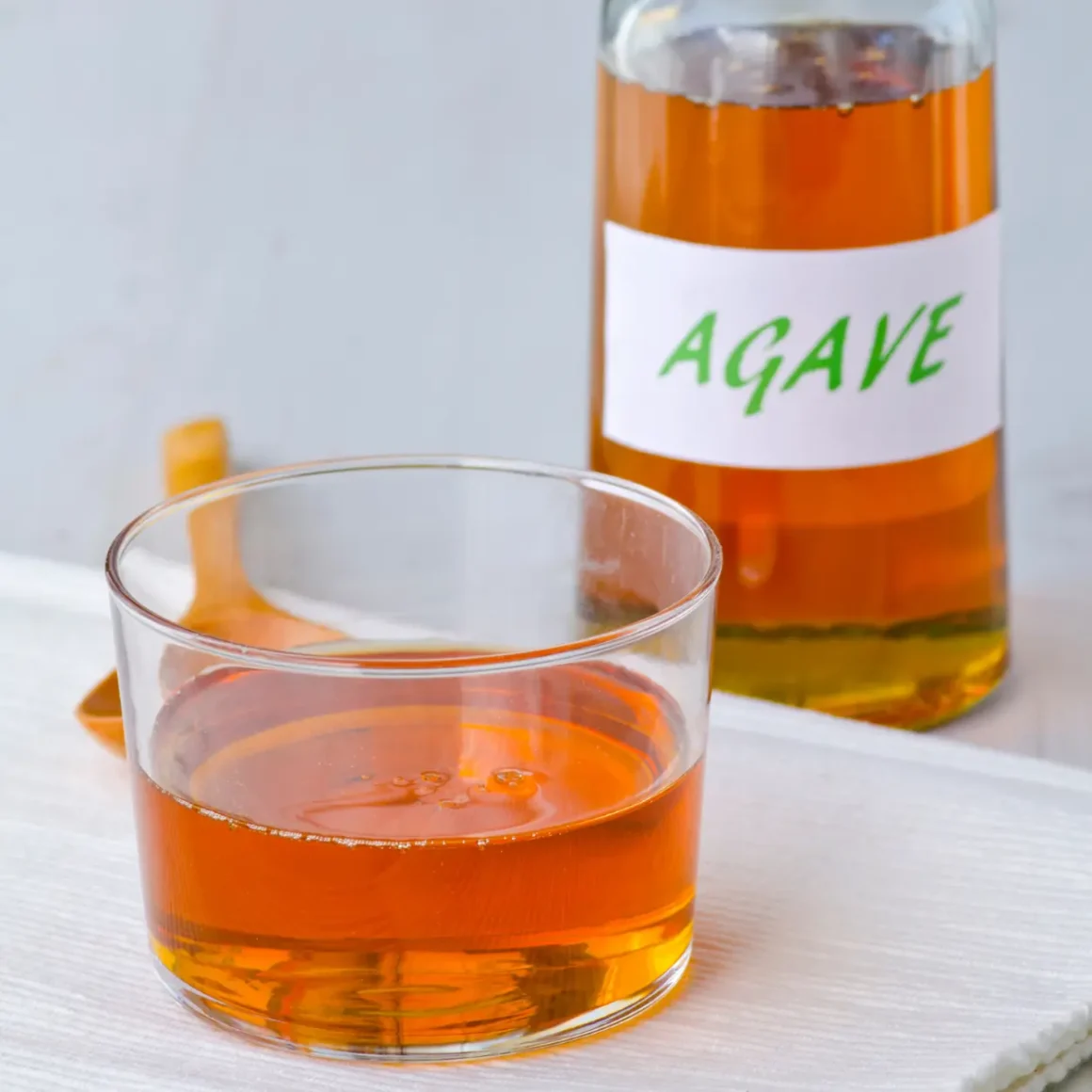 a glass of agave nectar next to a bottle of agave