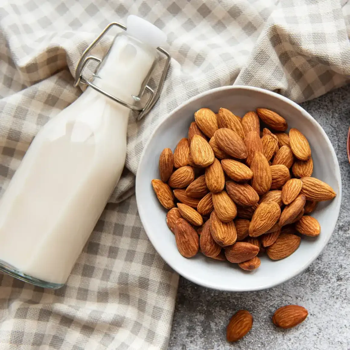 a bowl of almonds and a bottle of almond milk