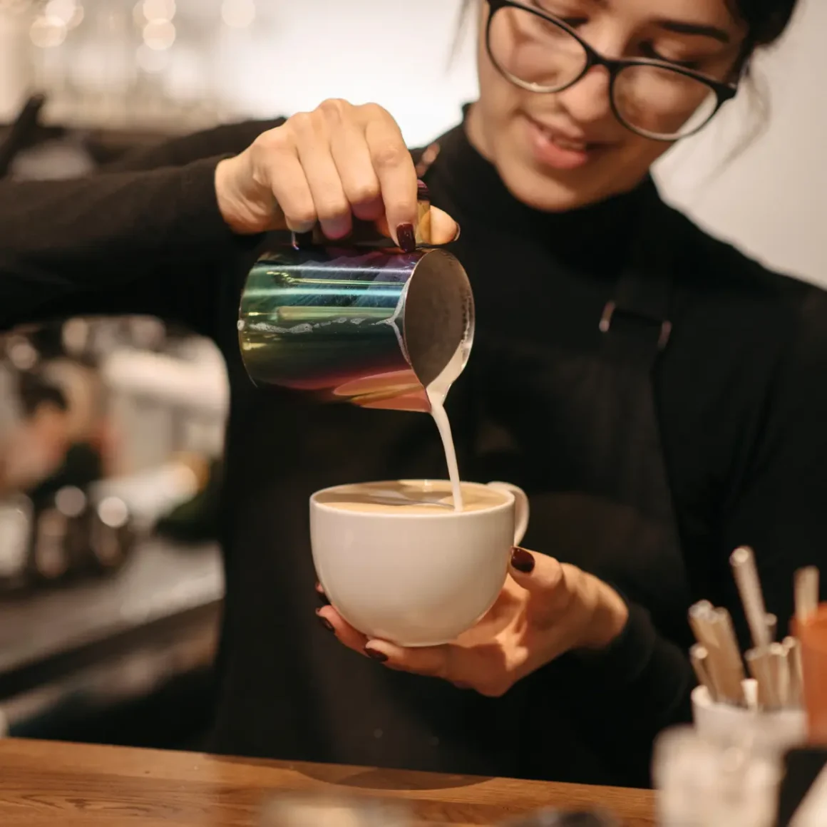 barista pouring milk into a cup of latte