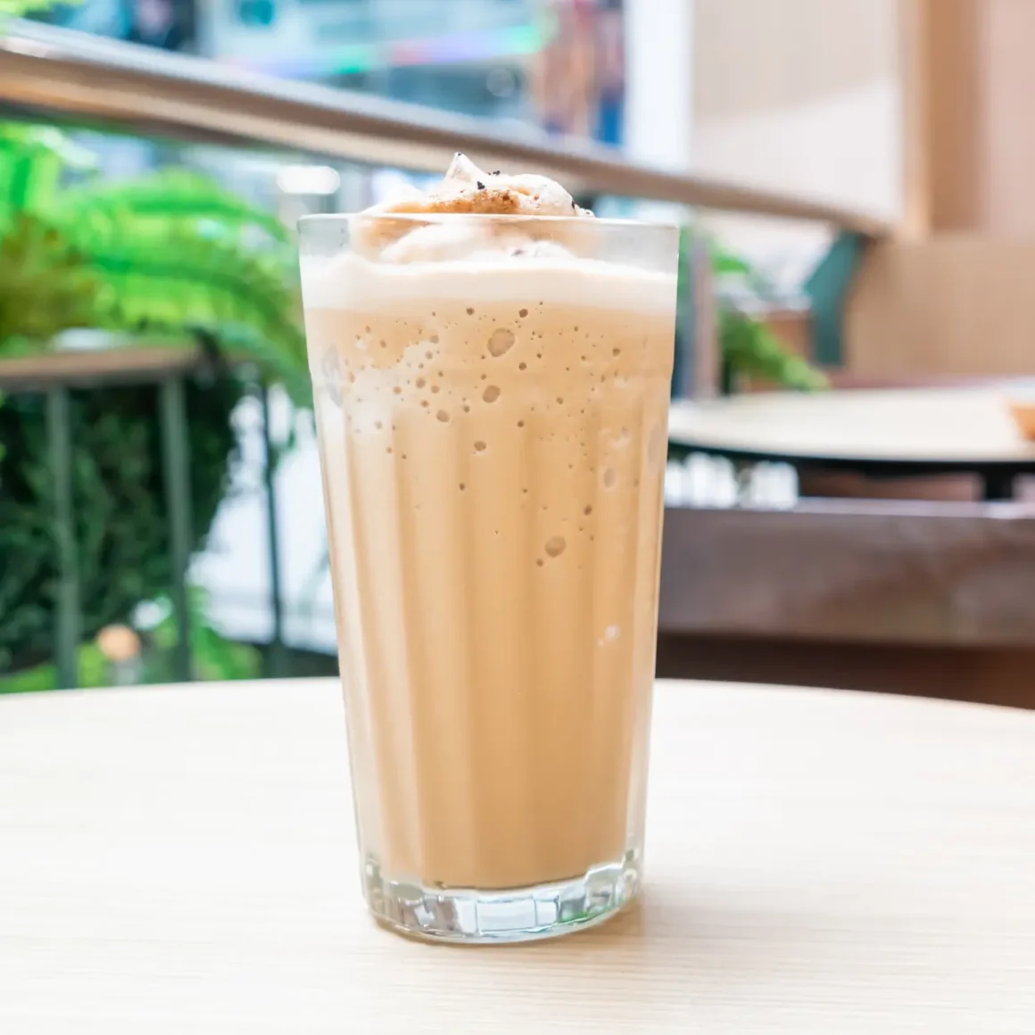 a glass of belened latte with cream on top