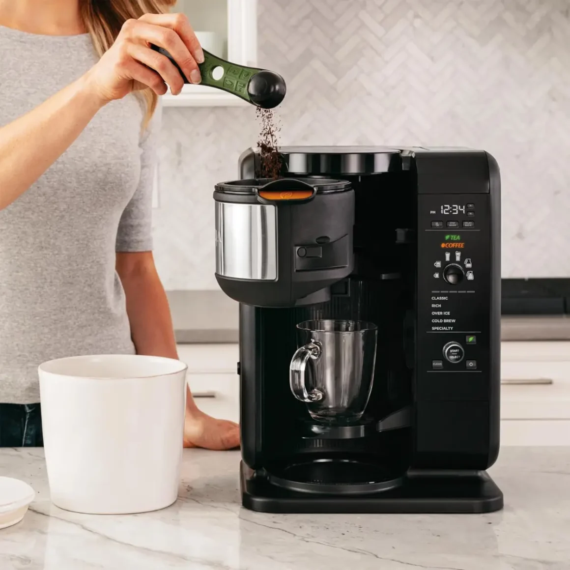 a woman pouring coffee into a ninja cp307 coffee maker