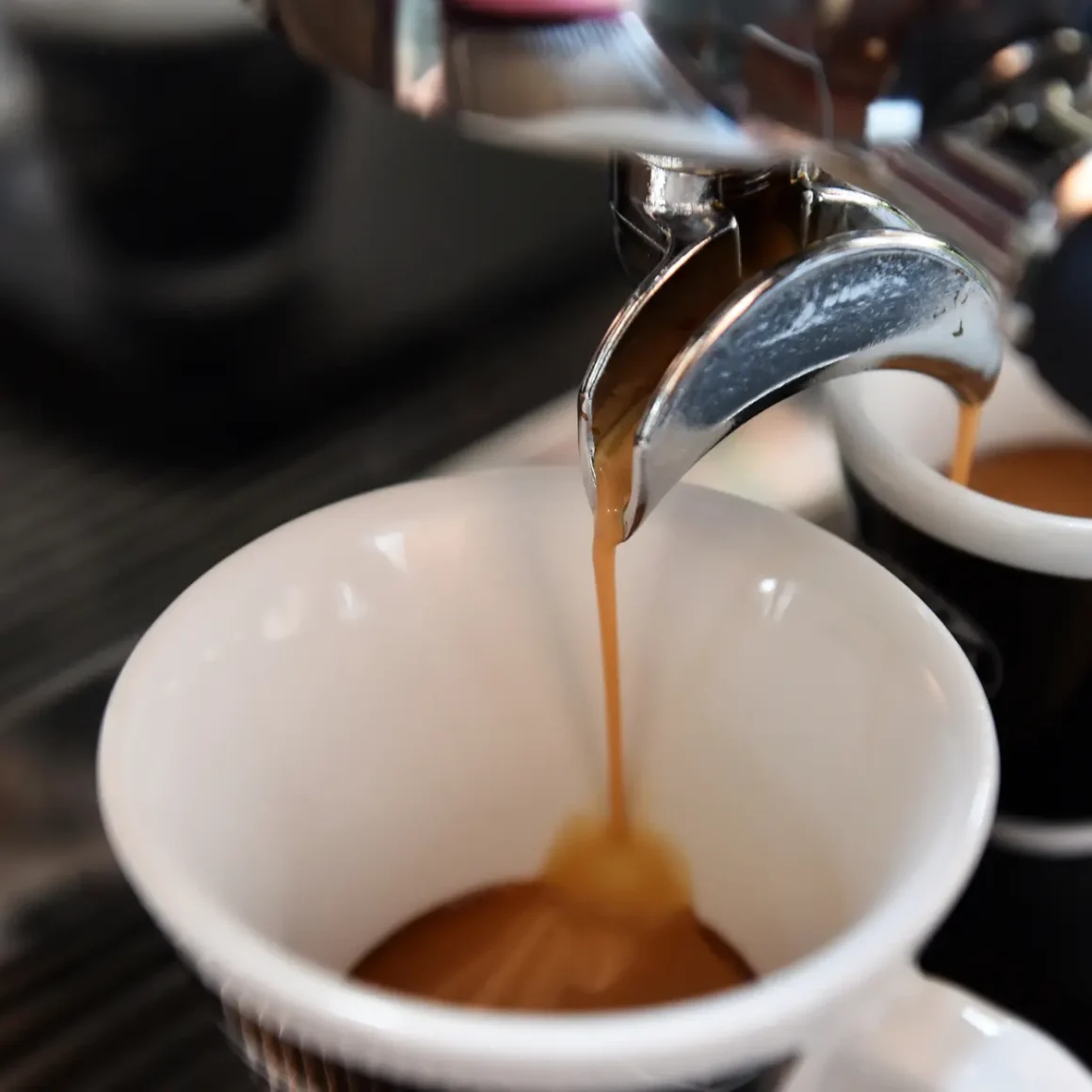 a coffee machine pouring cafe con leche into a cup