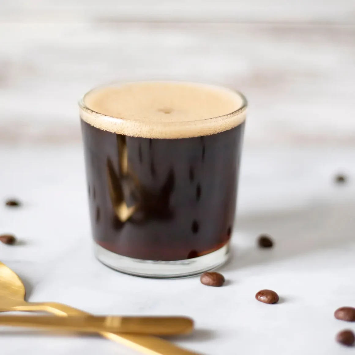 a glass of doppio americano with a foamy liquid