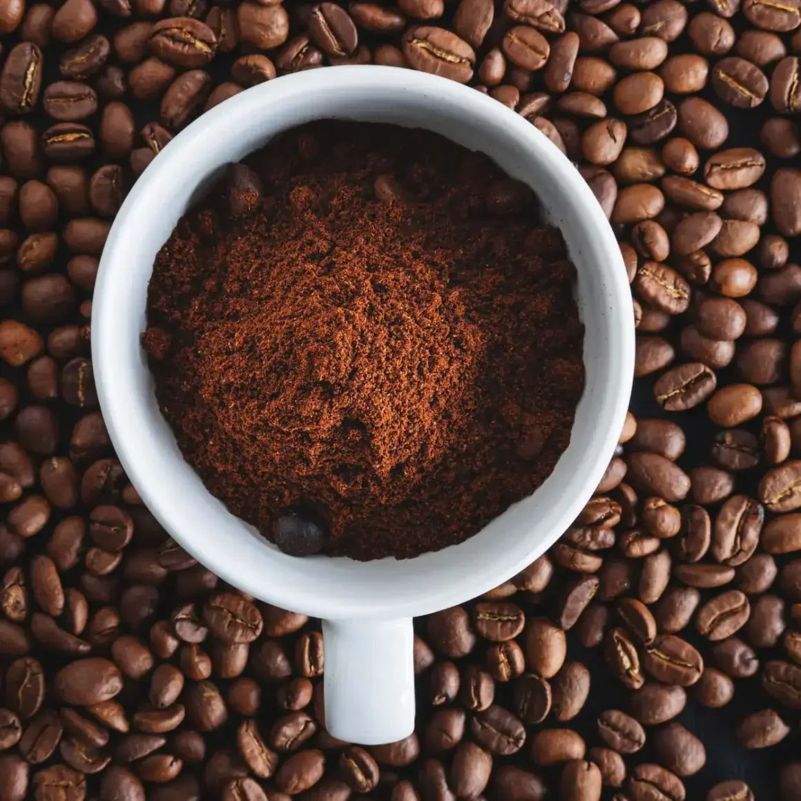 a cup of espresso powder in a pile of coffee beans