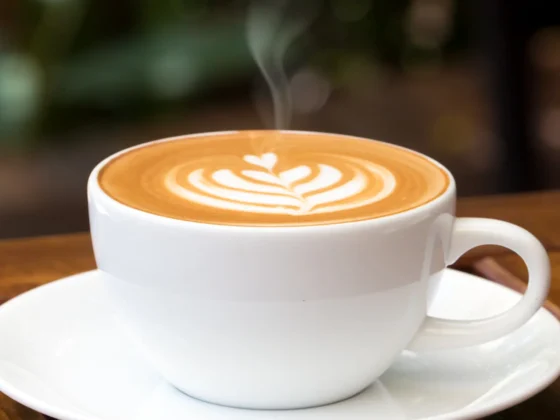 a cup of hot latte with a leaf design on top