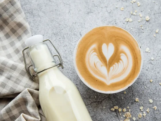 a bottle of oat milk and a cup of oat milk cappuccino