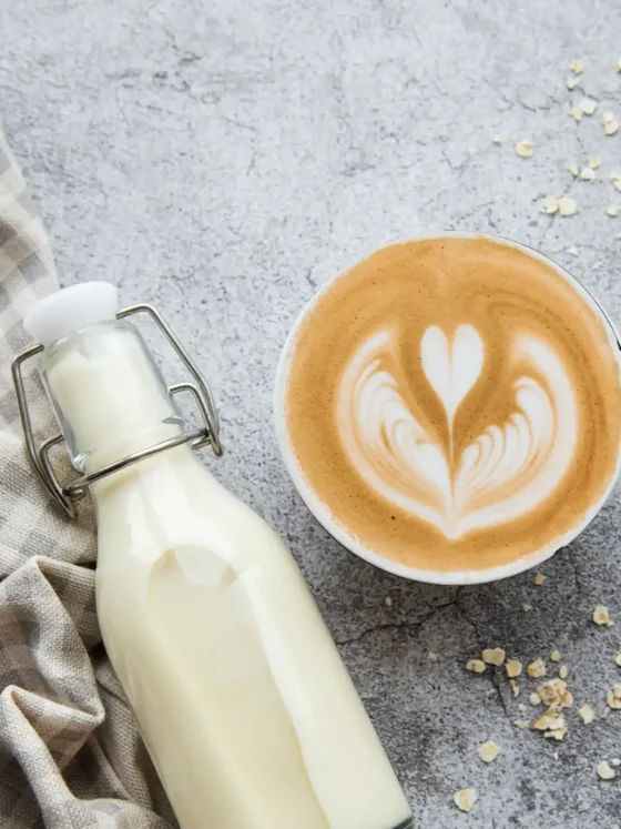 a bottle of oat milk and a cup of oat milk cappuccino