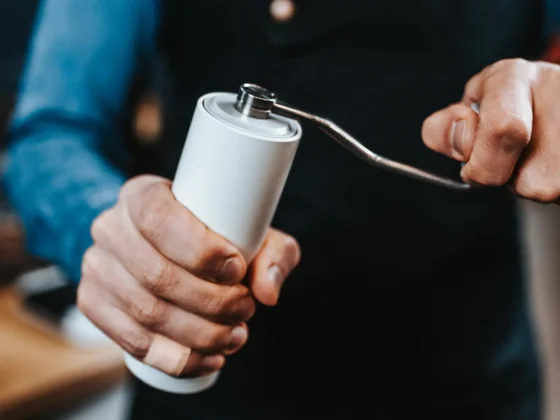 barista holding a white coffee grinder