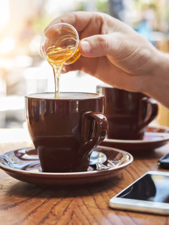 a person pouring a coffee sweetner into a cup of coffee
