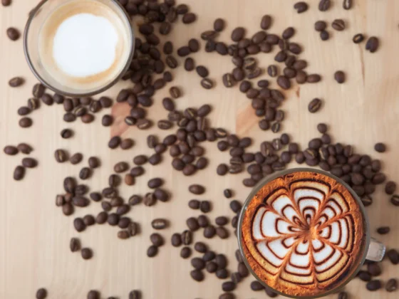 a coffee cup of mocha and a glass of macchiato over coffee beans on the table