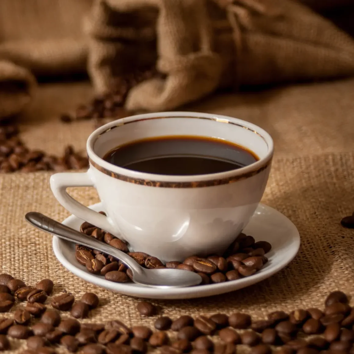 a cup of coffee on a saucer with coffee beans