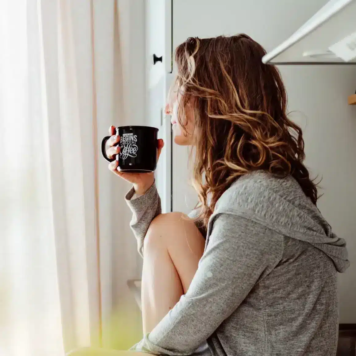 a woman sitting on a kitchen counter holding an instant espresso coffee mug