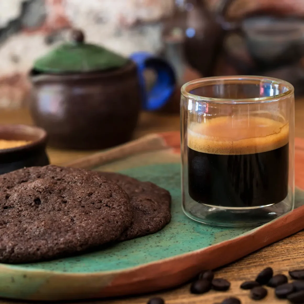 a glass of doppio espresso next to a plate of cookies