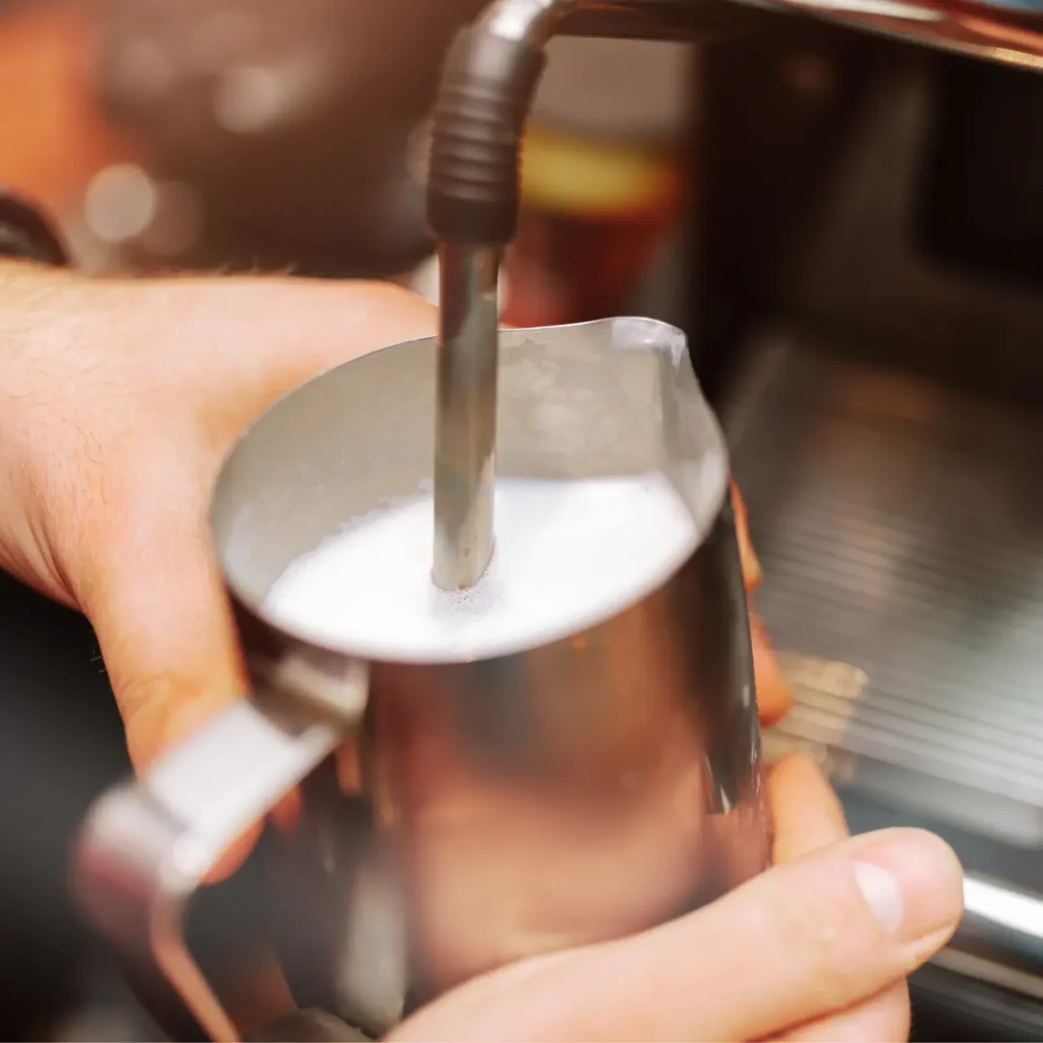 barista forthing milk in a metal pitcher