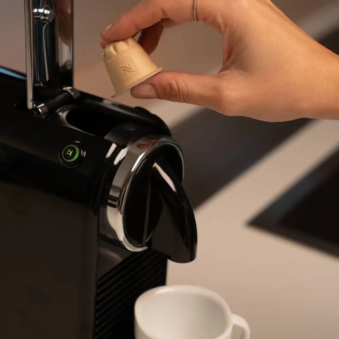 a hand holding a capsule in a nespresso citiz espresso machine