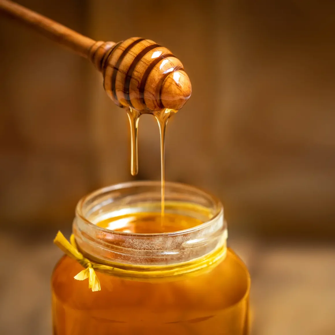 a honey dripping from a wooden stick