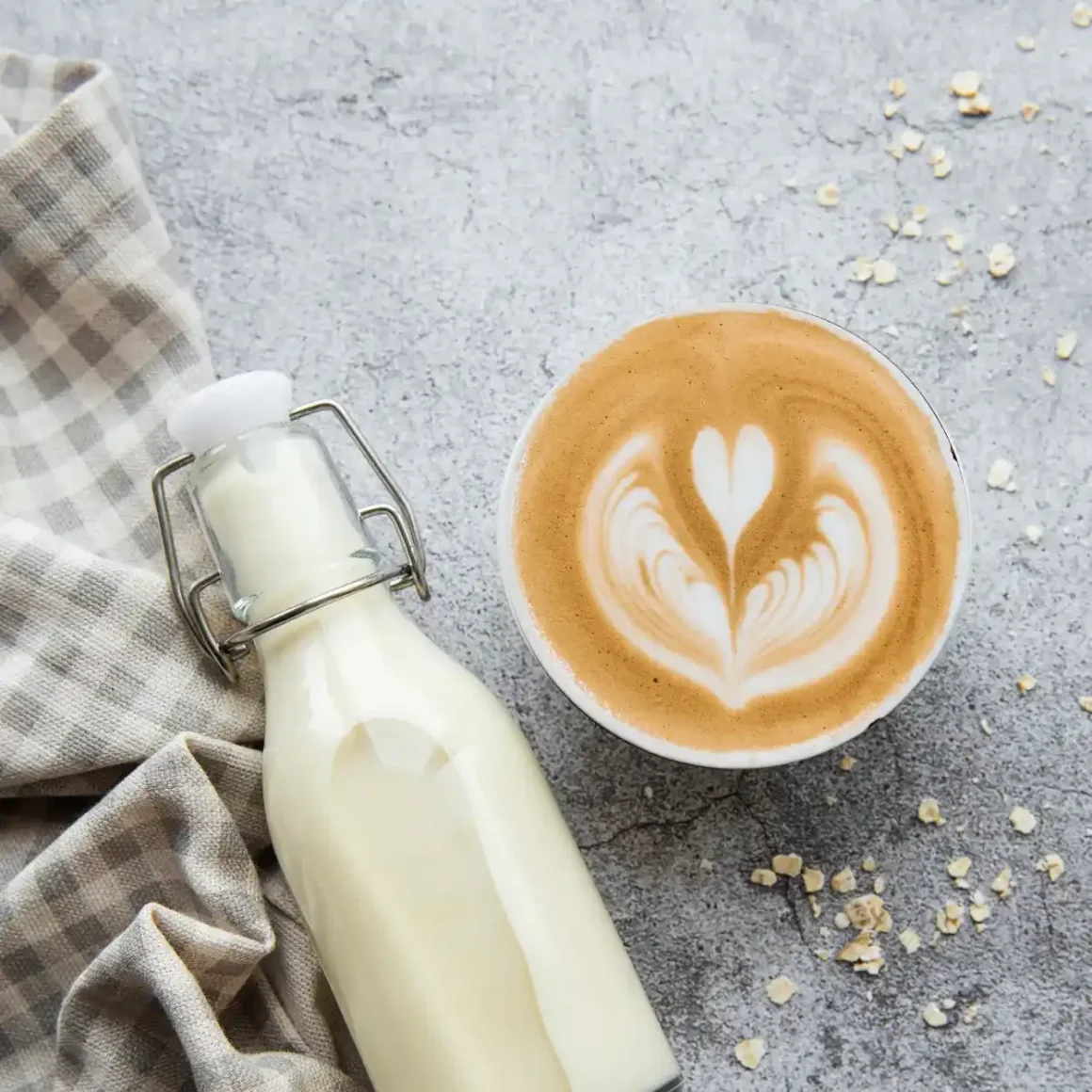 a bottle of oat milk and a cup of oat milk cappuccino