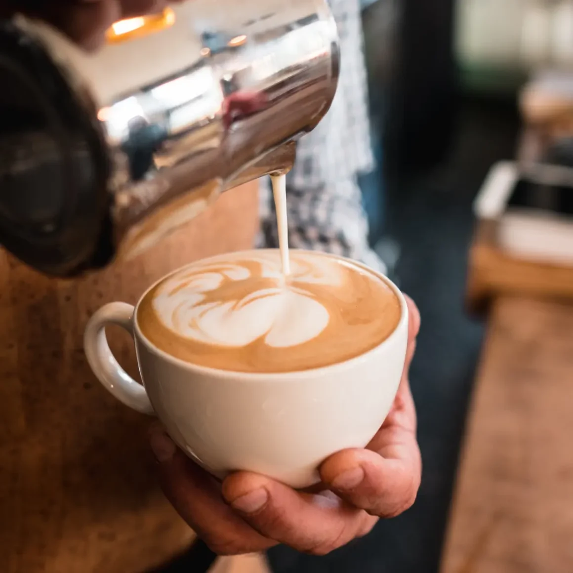 barista pouring milk into a cup of latte