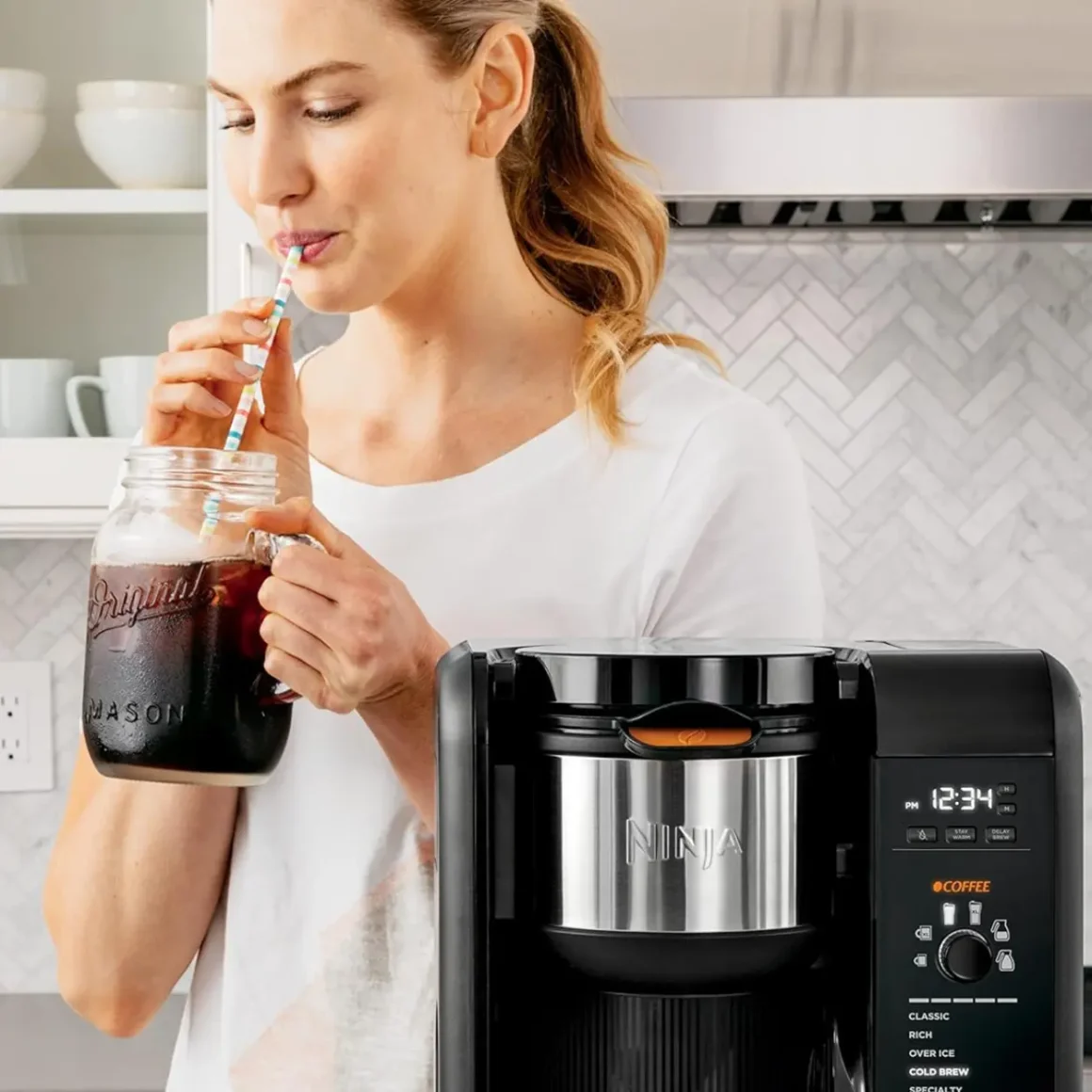 a woman drinking coffee from a jar with a straw