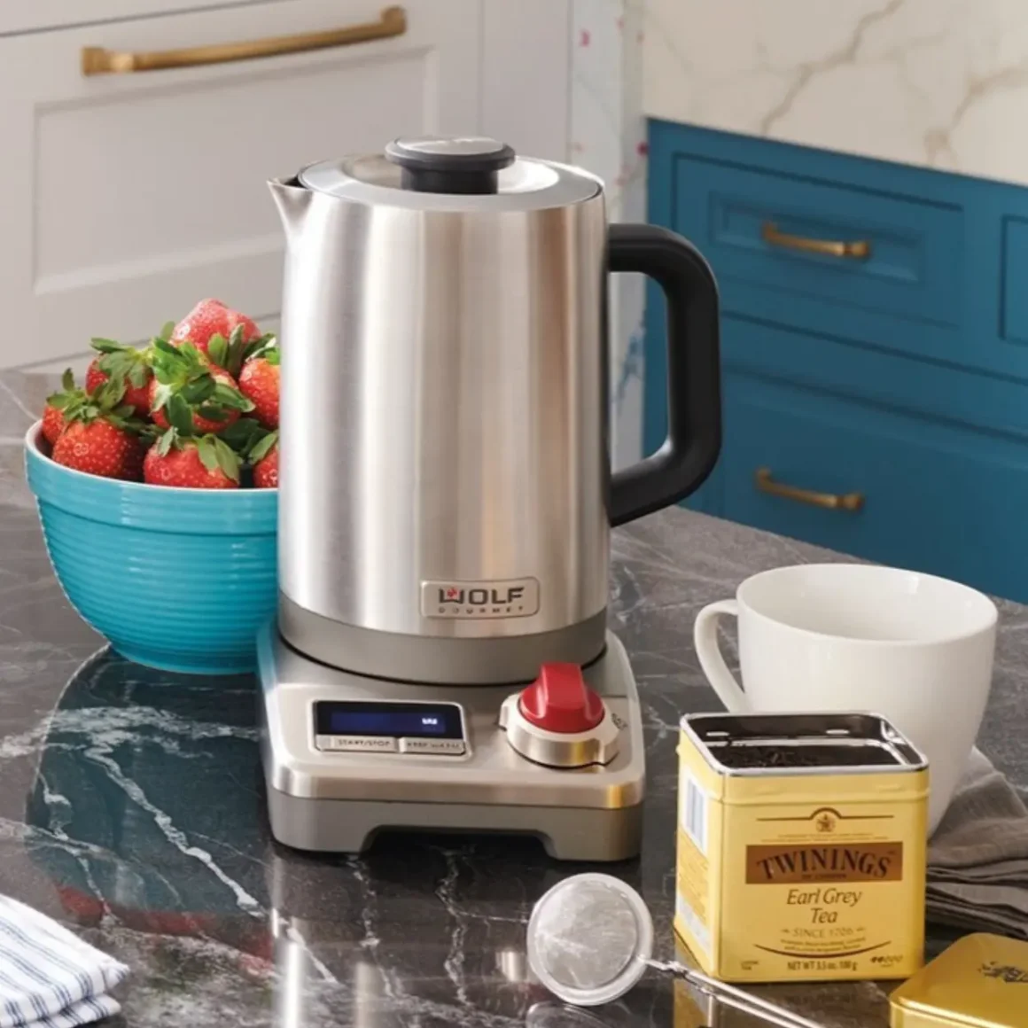 a wolf gourmet true temperature electric kettle and a bowl of strawberries on a counter