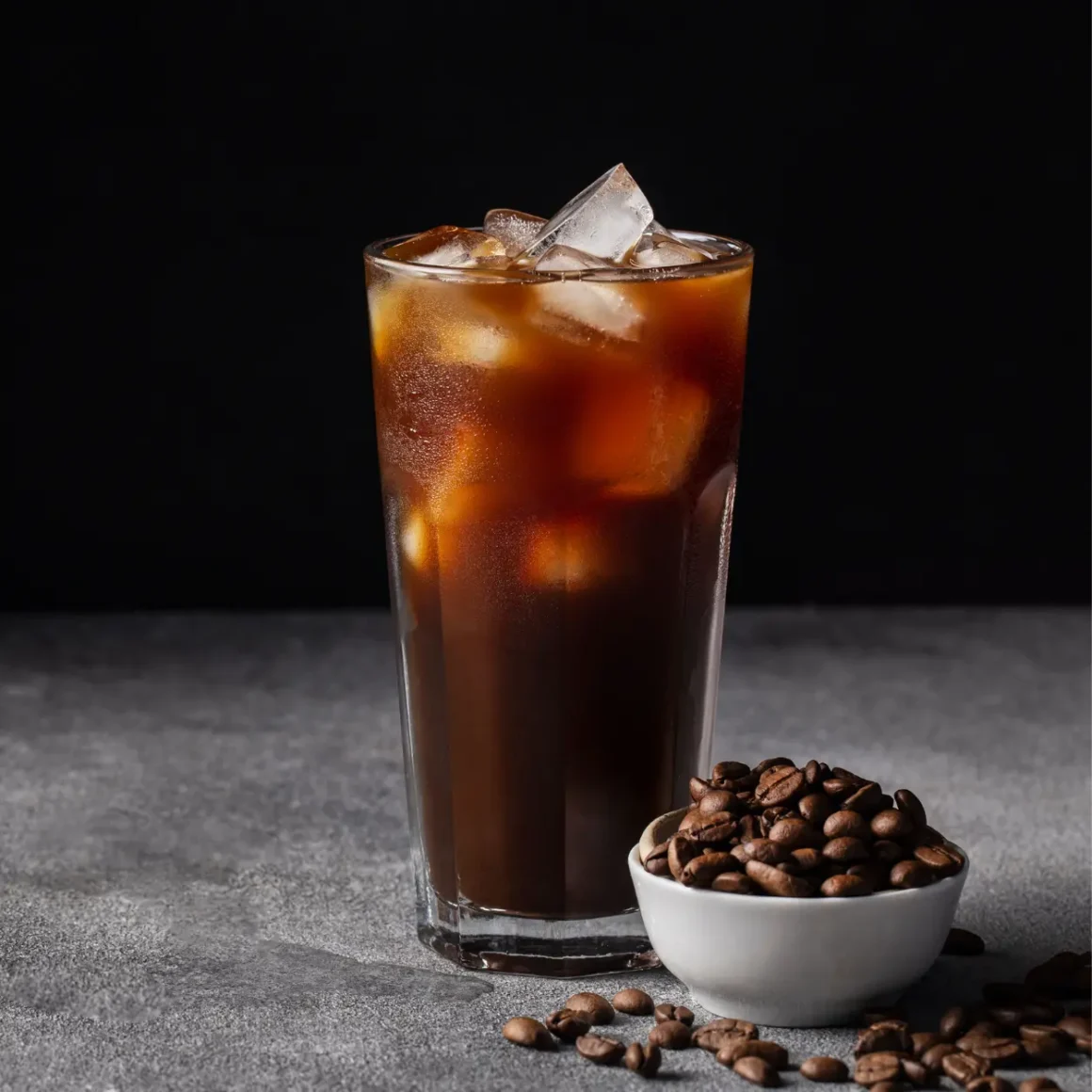a glass of ice coffee with vanilla extract and a bowl of coffee beans