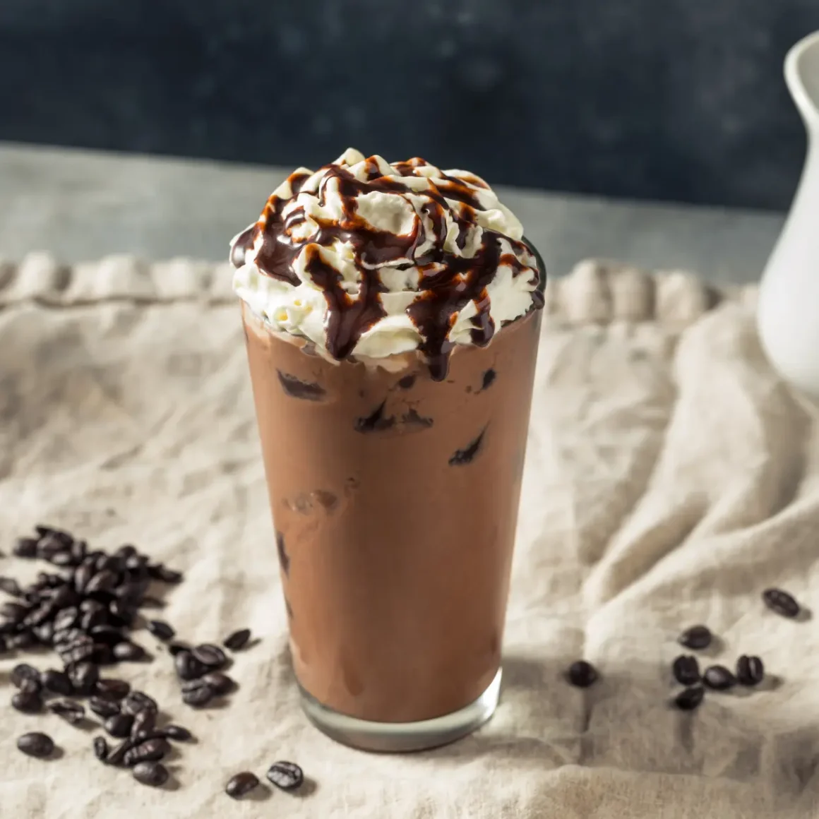 a glass of iced latte with whipped cream and beans